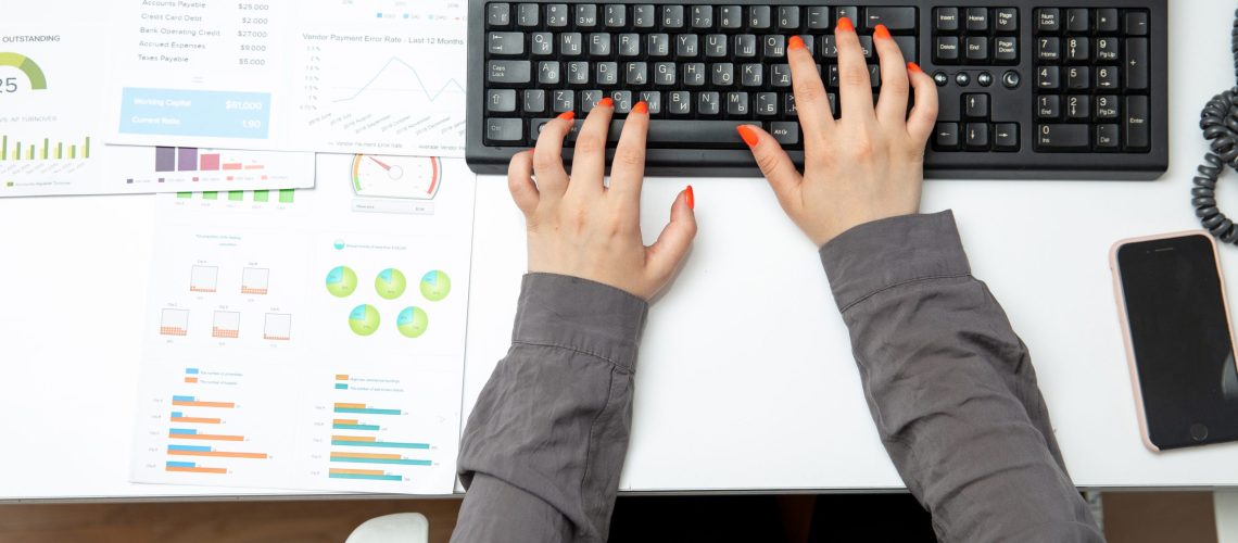 top-view-young-businesswoman-working-her-laptop-table-along-with-phone-graphics-job-activities-technology